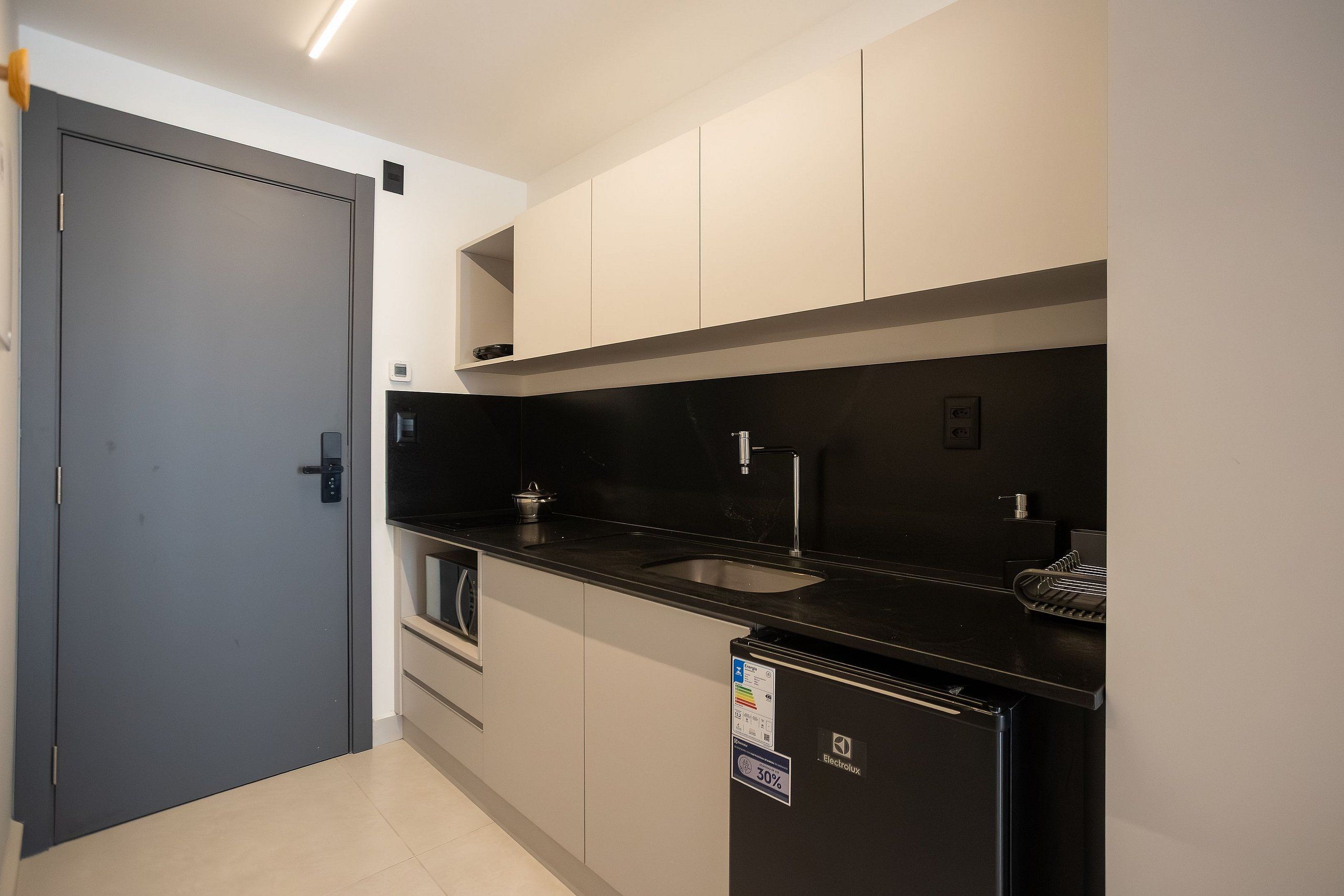 A modern kitchen with a black countertop, a sink, and a refrigerator.