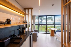 A modern kitchen with a view of the ocean, a dining area with a table and chairs, and a sofa. - Azimut With Direct Beach Access and Sea View by Carpediem (Cabedelo)
