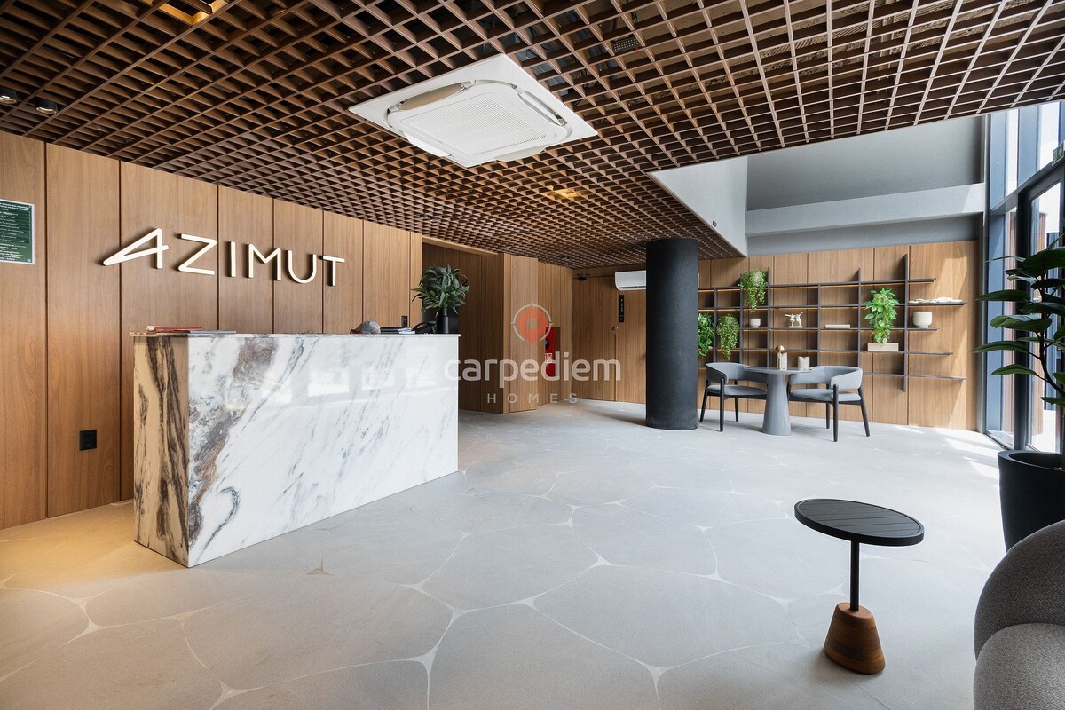 A reception area with a marble counter, wooden paneling, a grid ceiling, and a seating area with a table and chairs.