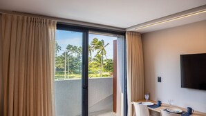 A hotel room with a balcony, a dining area with a table set for two, and a flat-screen TV mounted on the wall. - Azimut With Direct Beach Access and Sea View by Carpediem (Cabedelo)