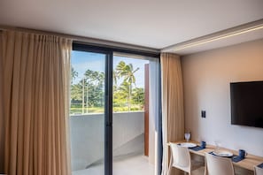 A hotel room with a balcony, a dining area with a table set for two, and a flat-screen TV mounted on the wall. - Azimut With Direct Beach Access and Sea View by Carpediem (Cabedelo)