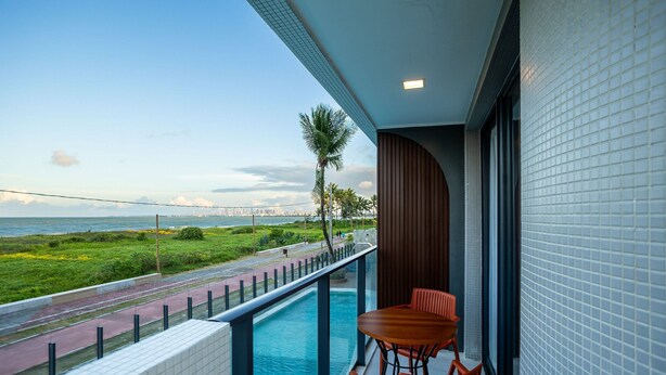 A balcony with a pool, a table, and chairs. - Azimut With Direct Beach Access and Sea View by Carpediem (Cabedelo)