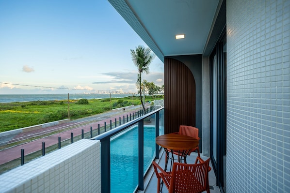 A balcony with a pool, a table, and chairs. - Azimut With Direct Beach Access and Sea View by Carpediem (Cabedelo)