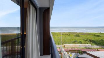 Uma varanda com vista para o oceano, uma piscina e uma área gramada.