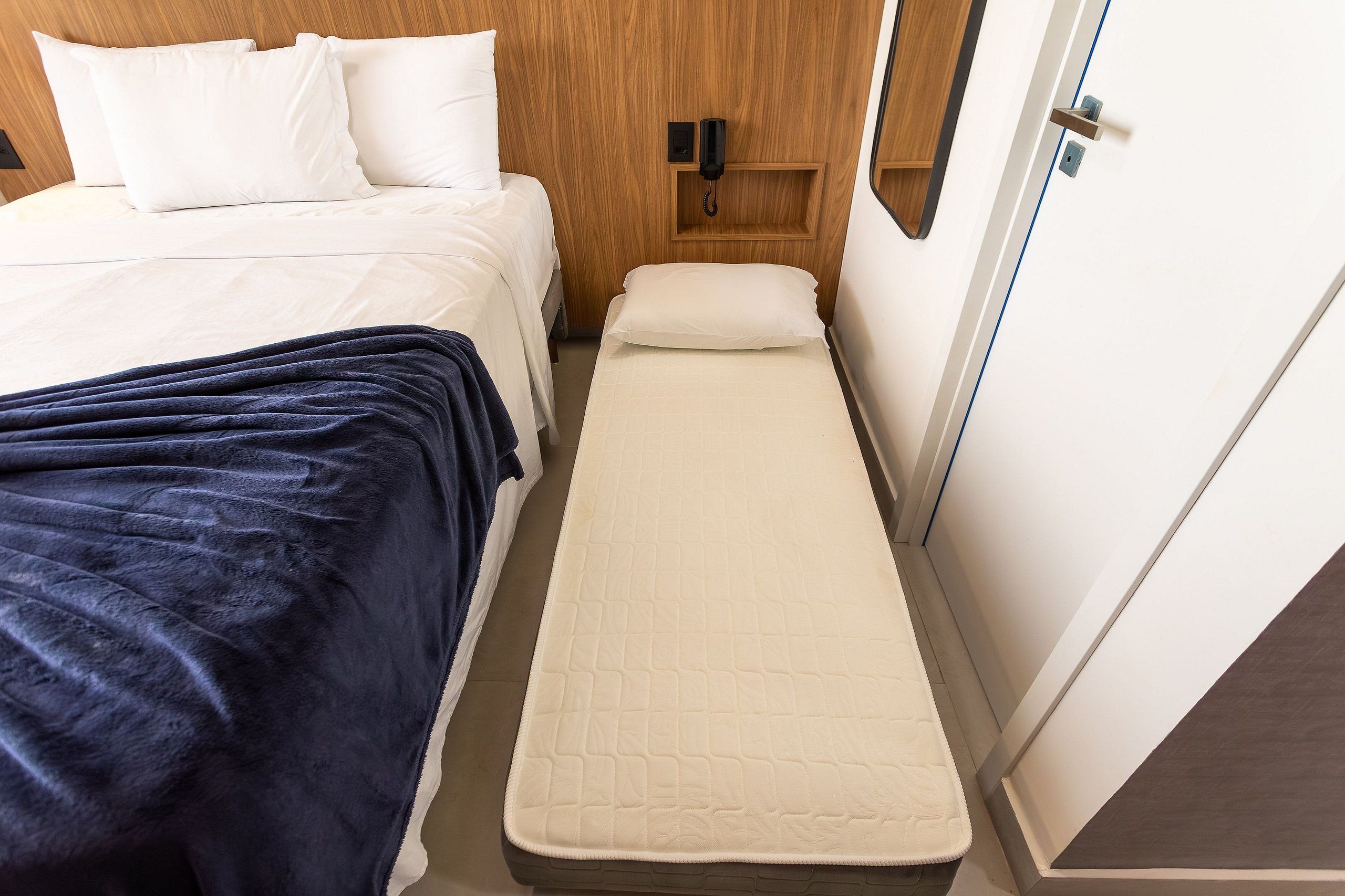 Une chambre d’hôtel avec un lit double, un lit simple et une armoire.