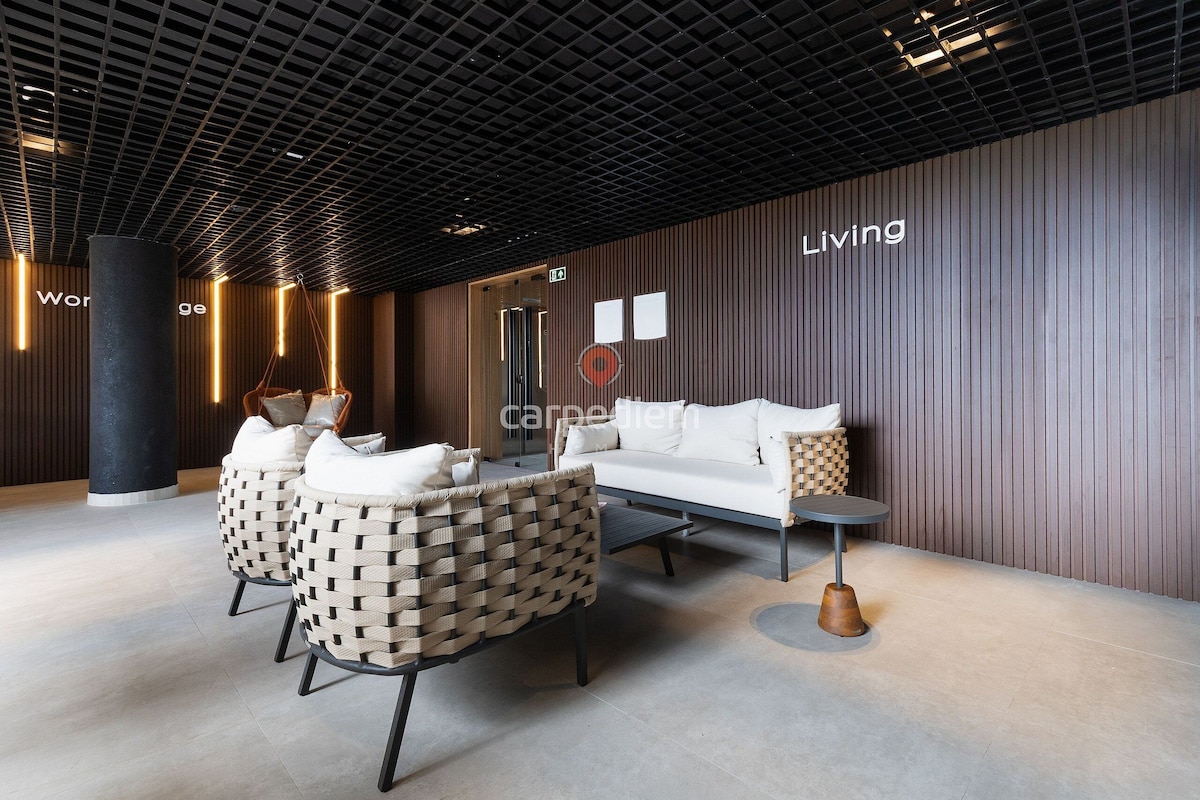 A modern lobby with a sofa, chairs, a coffee table, and a pillar.