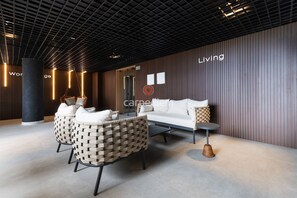 A modern lobby with a sofa, chairs, a coffee table, and a pillar. - Azimut With Direct Beach Access and Sea View by Carpediem (Cabedelo)