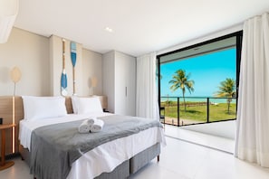 Habitació d'hotel moderna amb un llit gran, vistes a l'oceà i un balcó amb barana.
