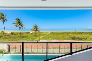 A balcony with a view of a beach, palm trees, and a clear blue sky. - Azimut With Direct Beach Access and Sea View by Carpediem (Cabedelo)