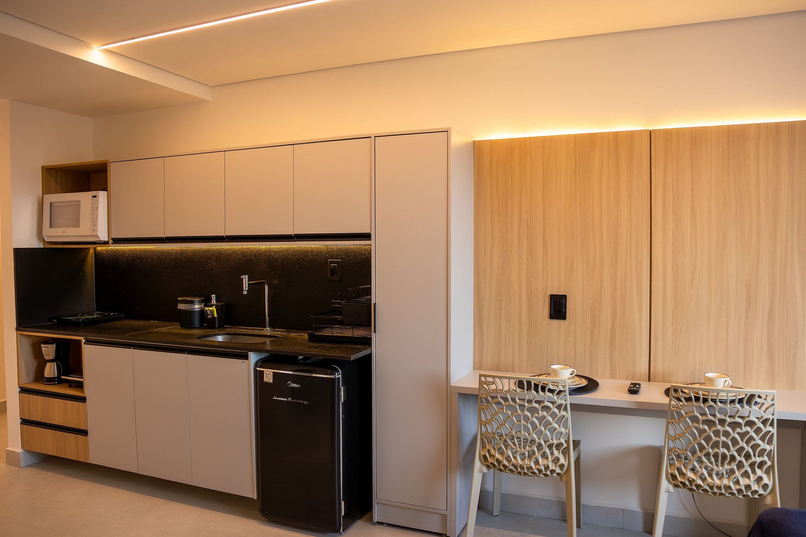 A modern kitchen with a built-in microwave, a coffee machine, and a refrigerator.
