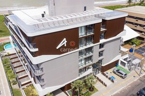 Un edificio moderno de varios pisos con terraza en la azotea, piscina y estacionamiento.