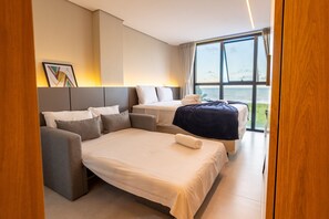 A modern hotel room with a large bed, a sofa, and a view of the sea through large windows. - Azimut With Direct Beach Access and Sea View by Carpediem (Cabedelo)