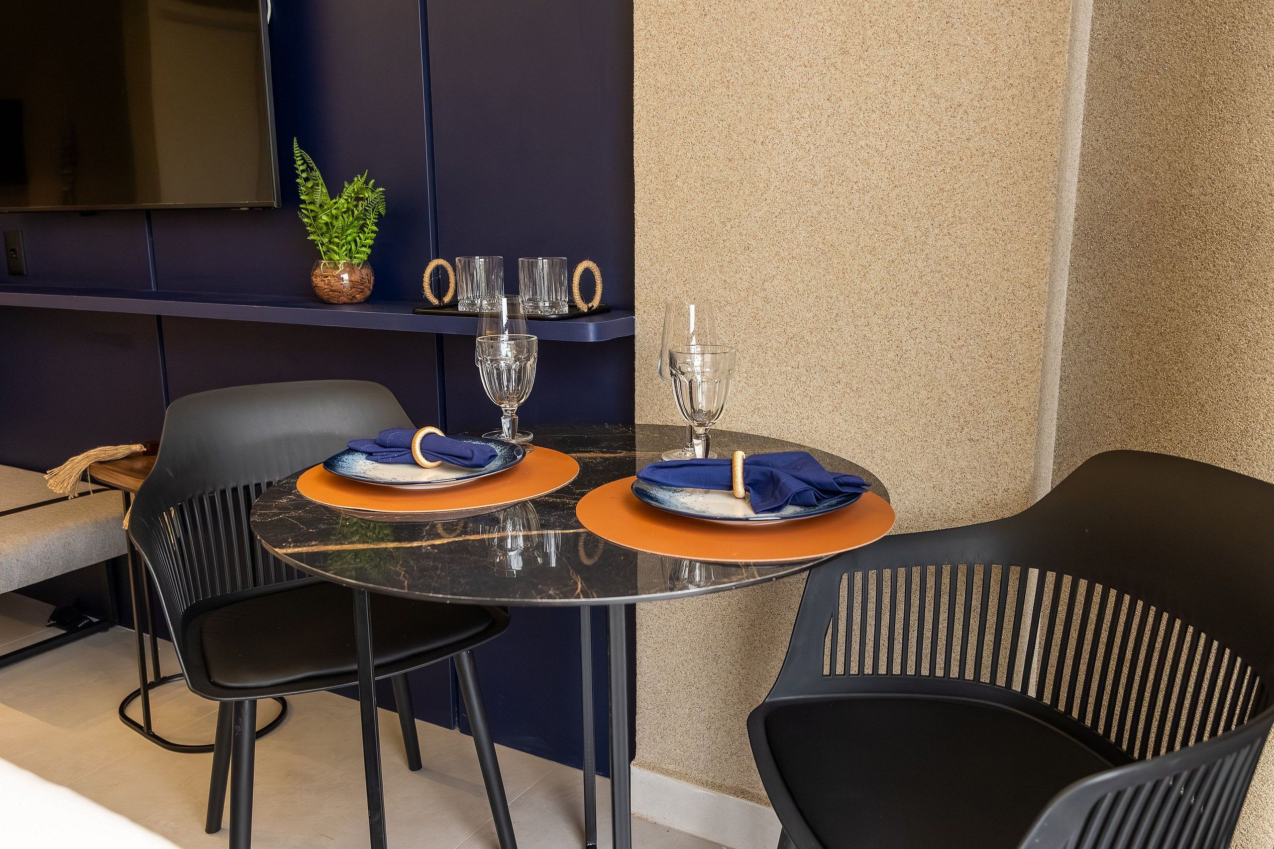 A modern dining area with a round table, two chairs, and a small potted plant.