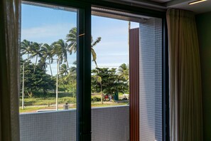 Vista a través de una ventana que muestra palmeras y una zona delimitada por una valla.