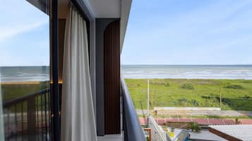 Uma varanda com vista para o oceano, uma piscina e uma área gramada.