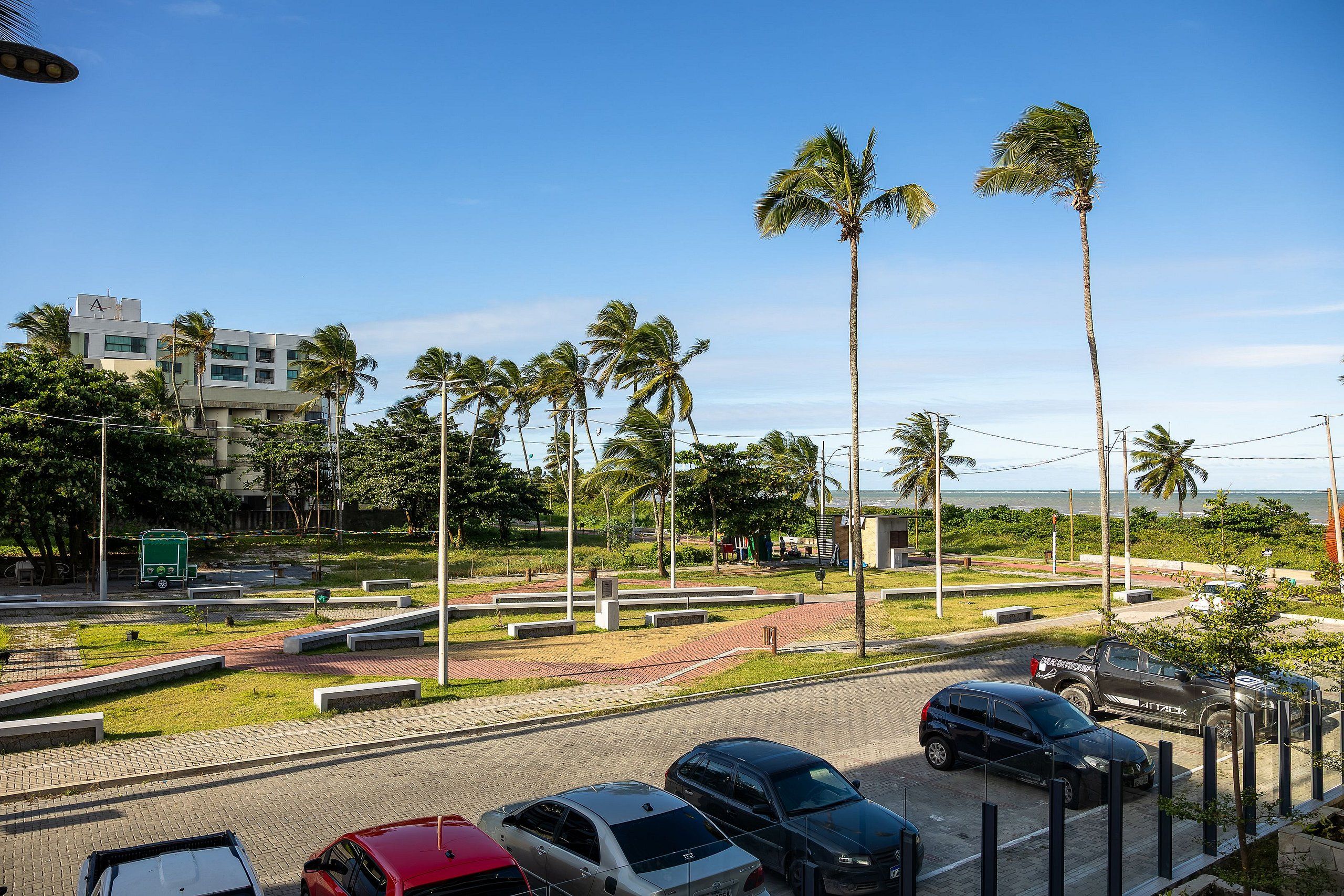 A parking area with multiple cars, palm trees, and a building with a visible 'A' on the roof.