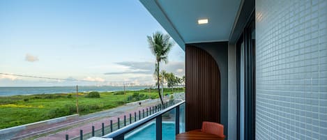 A balcony with a pool, a table, and chairs.