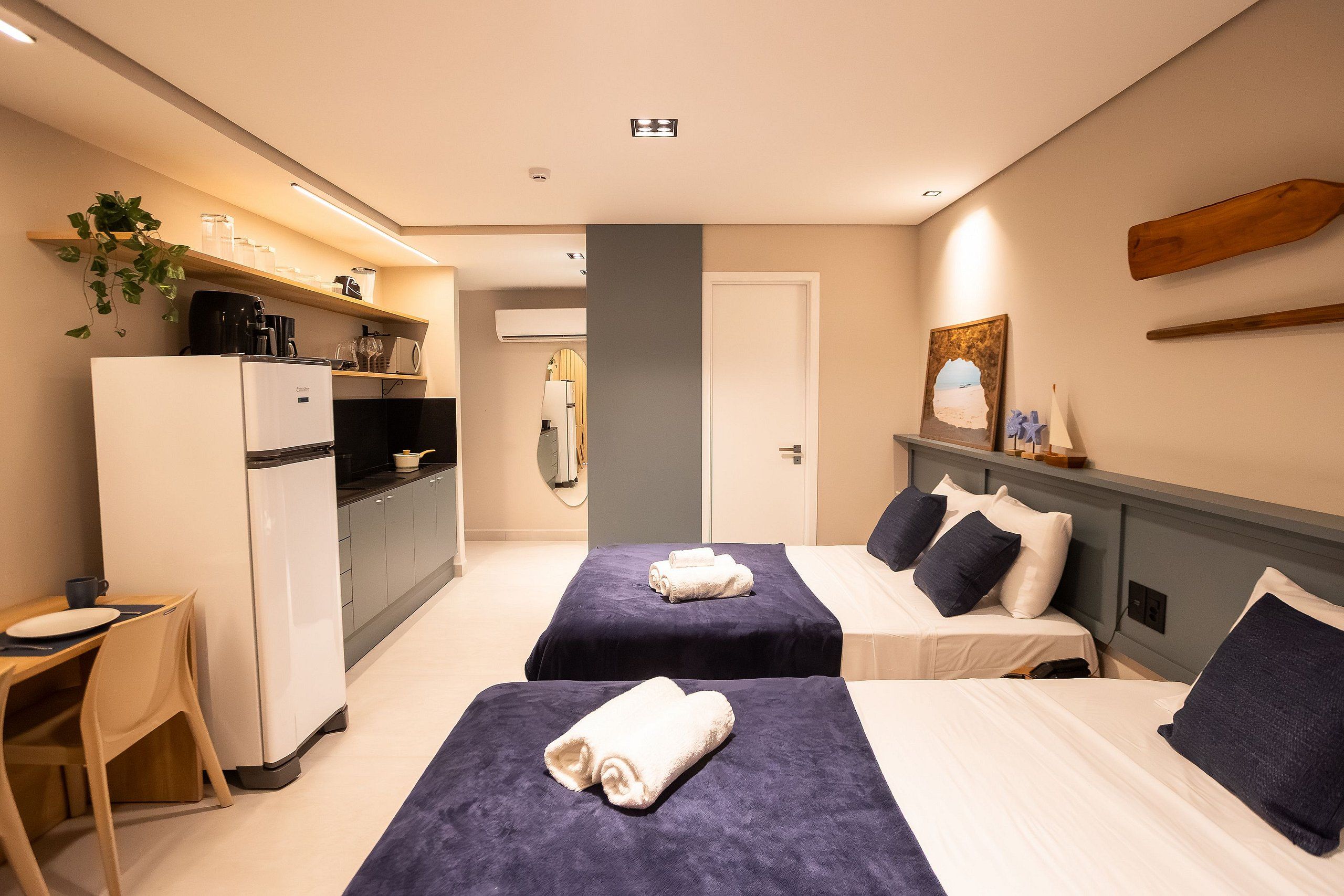 Habitación de hotel con dos camas, kitchenette, un pequeño comedor y baño.