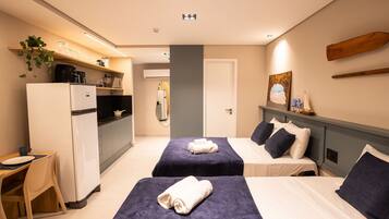 Habitación de hotel con dos camas, kitchenette, un pequeño comedor y baño.