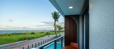 A balcony with a pool, a table, and chairs.