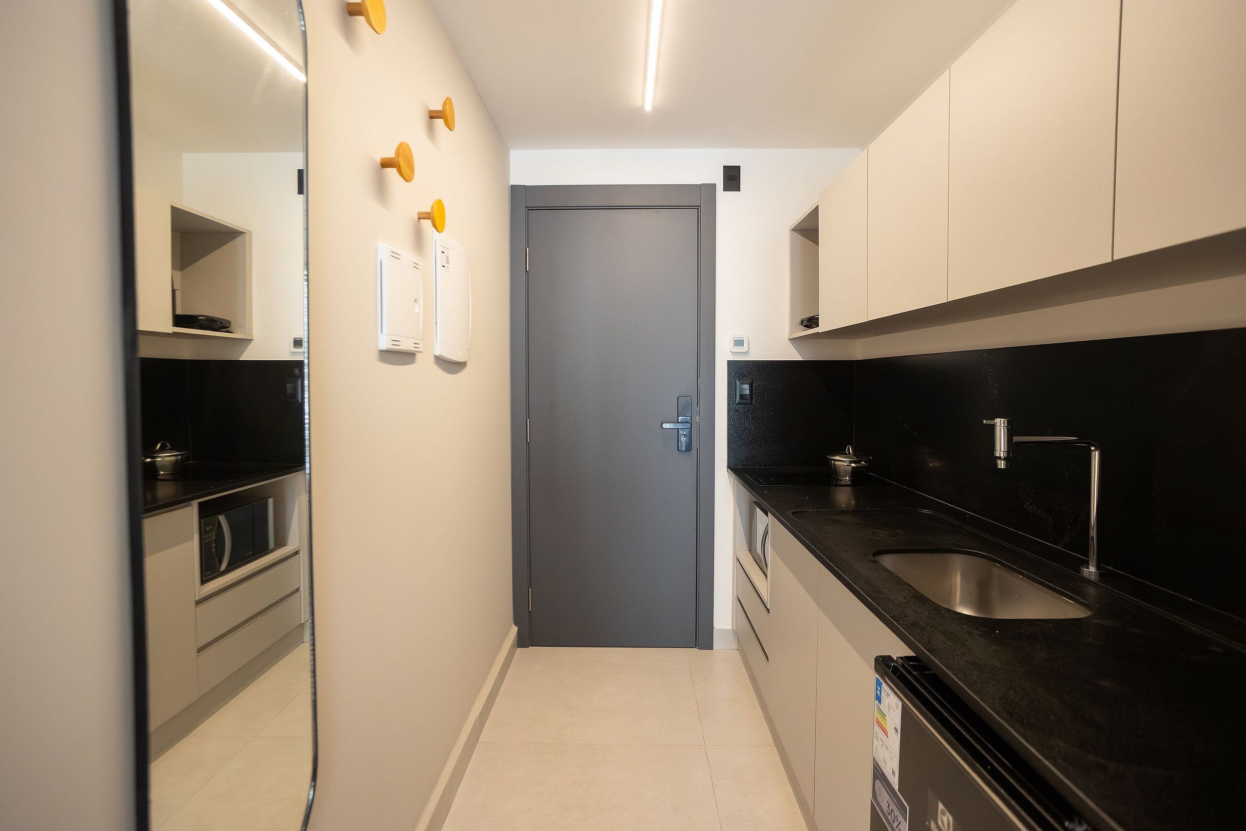 Cocina moderna con encimera negra, pileta de acero inoxidable y muebles bajos blancos.