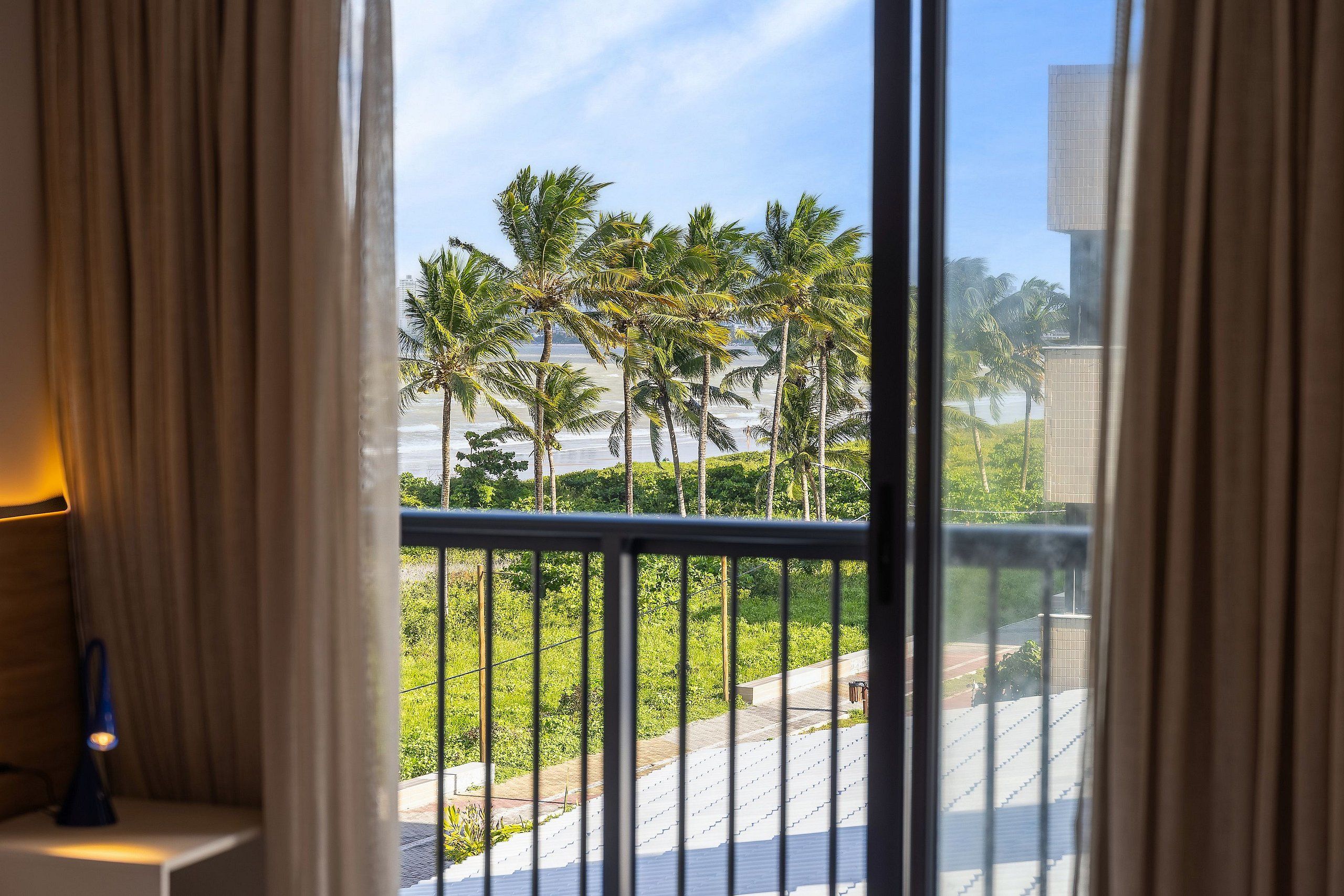 A balcony with a view of palm trees and a building.