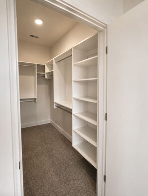 A walk-in closet with open shelves and a carpeted floor.