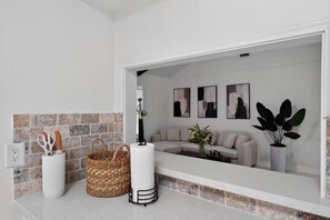 Ein modernes Badezimmer mit einem weißen Waschbecken, einem Korbwannenkorb und einer weißen Vase.