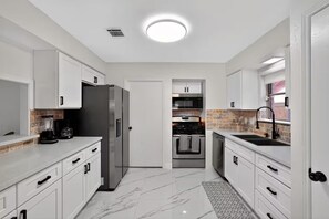 A modern kitchen with white cabinets, a stainless steel refrigerator, a built-in oven, and a microwave. - Private Pool-Paradise - 5BR- Close to Everything (Houston)
