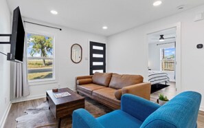 A modern living room with a sofa, a coffee table, a TV, and a view of the outdoors. - Modern 3-bedroom house with in charming Old Town Georgetown (Georgetown)