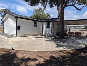 A single-story house with a covered patio area, a tree in front, and a clear sky.