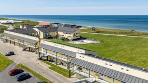 Un hotel junto a la costa con aparcamiento y vistas al mar.