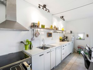 A modern kitchen with white cabinets, a stainless steel sink, and a range hood.
