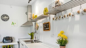 Una cocina moderna con encimera blanca, horno empotrado, fregadero y una zona de café con tazas y cafetera.
