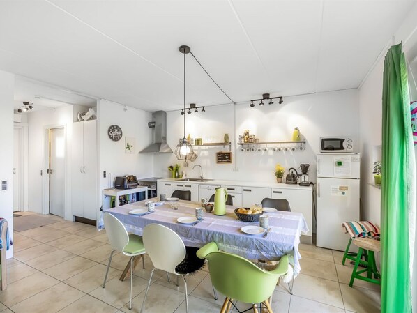 A compact kitchen with white cabinets, a dining table with chairs, and a microwave.