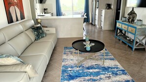 Una sala de estar con sofá, mesa de centro y vista a la cocina.