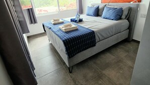 Un dormitorio moderno con una cama grande, vistas al verdor exterior y un cuadro en la pared.