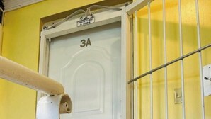 Valkoinen ovi, jossa on numero 3A, metallinen portti ja keltainen seinä.