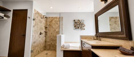 A modern bathroom with a walk-in shower, a large mirror, and a wooden vanity.