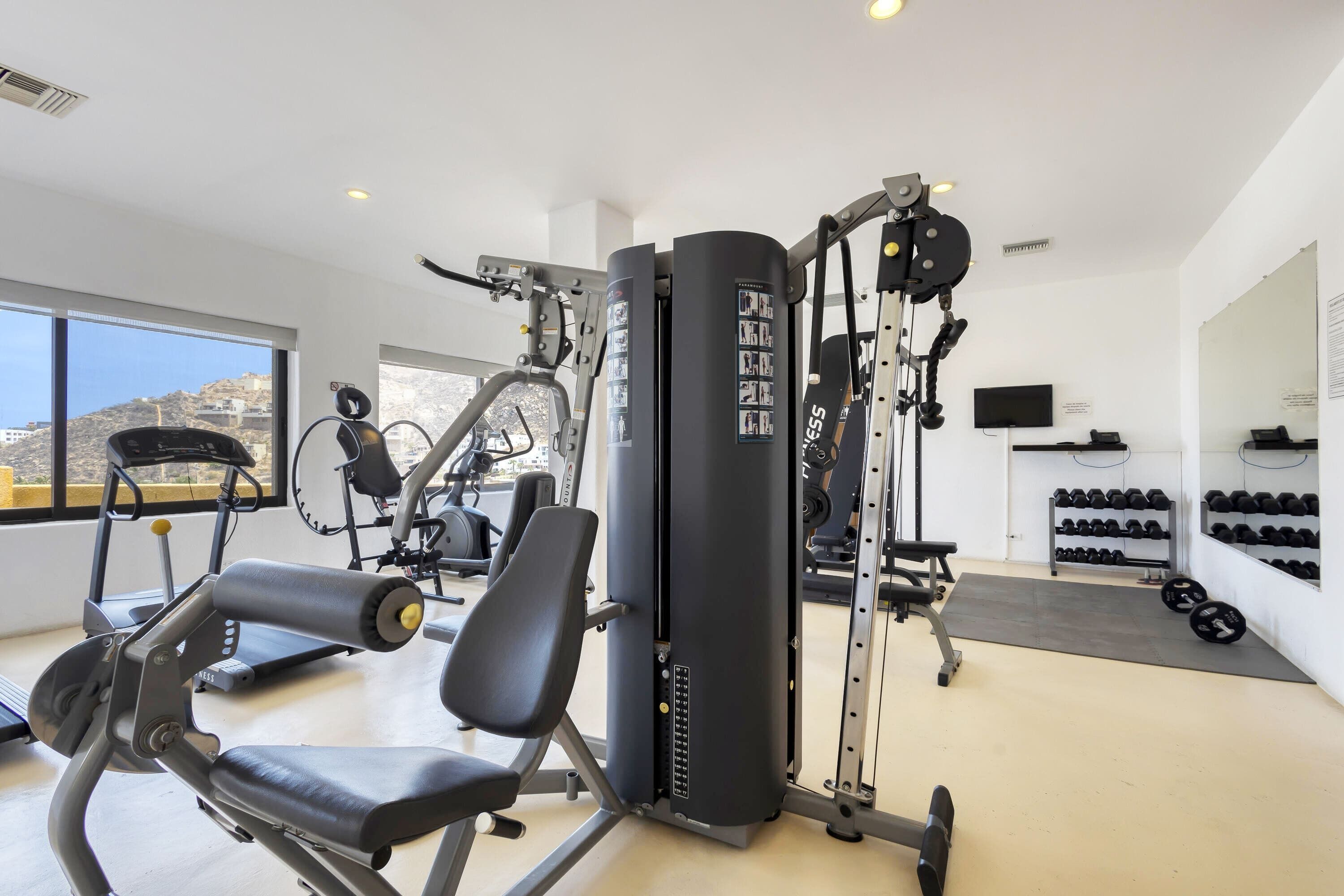 A gym with exercise equipment, a large window, and a wall-mounted TV.