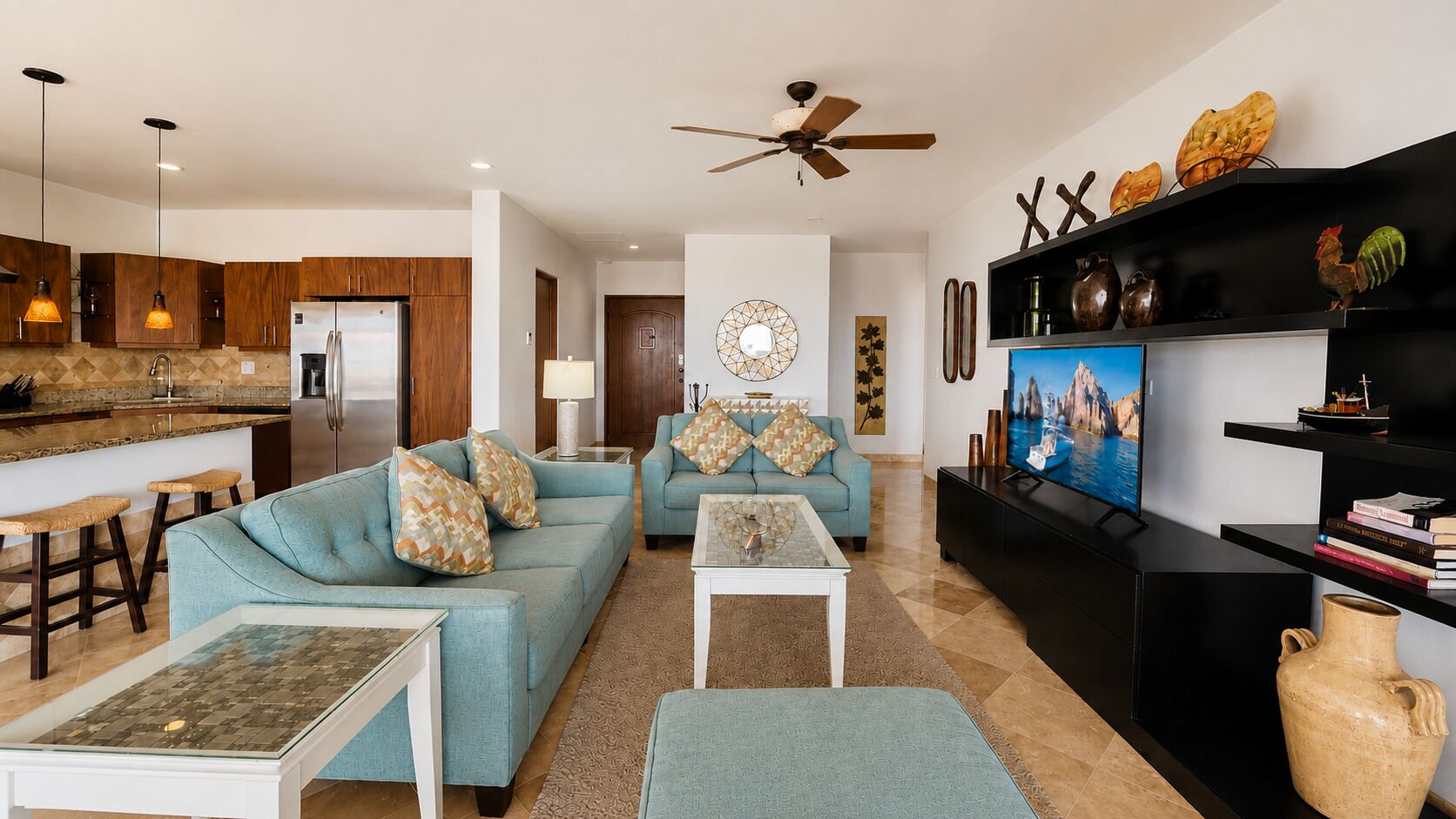 A modern living room with two sofas, a coffee table, a TV, and a kitchen area with wooden cabinets and a refrigerator.