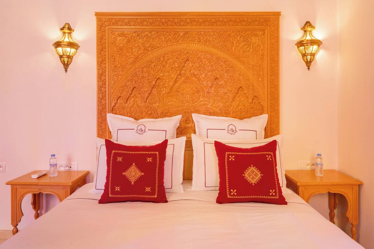 A hotel room with a large bed, two nightstands, and a decorative ceiling.