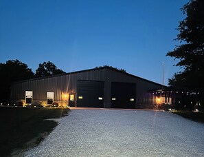 Un grand bâtiment industriel avec une allée en gravier et une entrée bien éclairée.