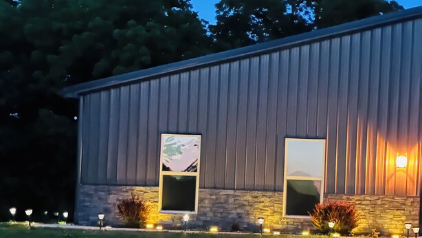 A building with two windows, a stone facade, and a grassy area in front. - The serenity studio near route 66 (Webb City)