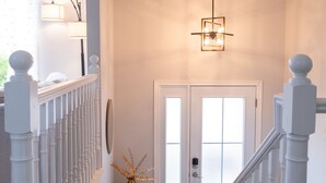 Eine Treppe mit weißen Balustraden, eine T ür mit Glasfeldern und einer Pendelleuchte.
