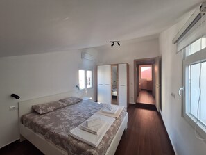 Ein Schlafzimmer mit Bett, Kleiderschrank, Spiegel und Fenster.
