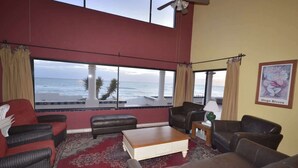 A living room with a large window overlooking the ocean, furnished with leather sofas and a coffee table. - Beachfront Home in Rocky Point Casa Alhaja (Puerto Peñasco)