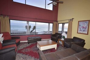 A living room with a large window overlooking the ocean, furnished with leather sofas and a coffee table. - Beachfront Home in Rocky Point Casa Alhaja (Puerto Peñasco)