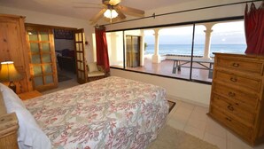 A bedroom with a bed, a ceiling fan, a dresser, and a view of the ocean. - Beachfront Home in Rocky Point Casa Alhaja (Puerto Peñasco)