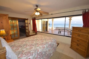 A bedroom with a bed, a ceiling fan, a dresser, and a view of the ocean. - Beachfront Home in Rocky Point Casa Alhaja (Puerto Peñasco)
